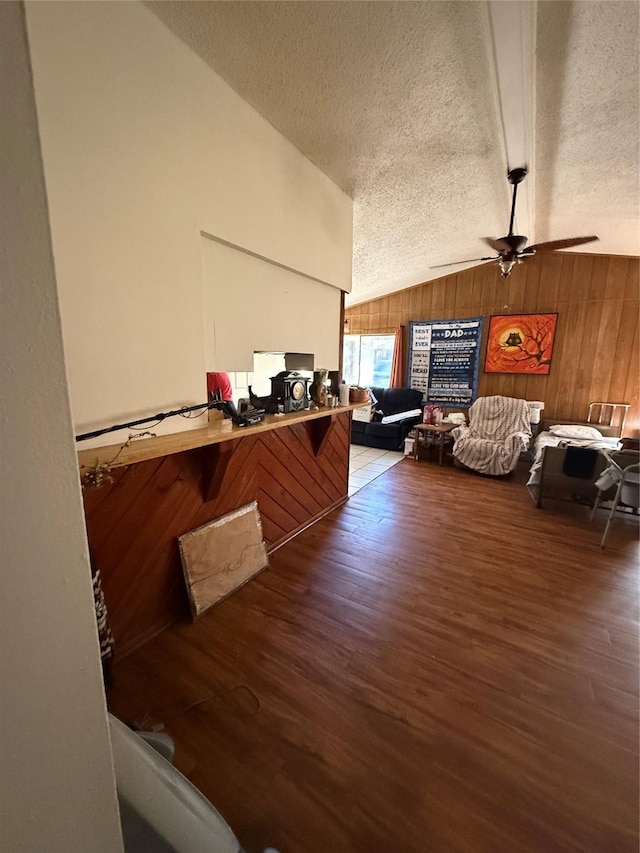 interior space with vaulted ceiling, wood walls, a textured ceiling, and wood-type flooring