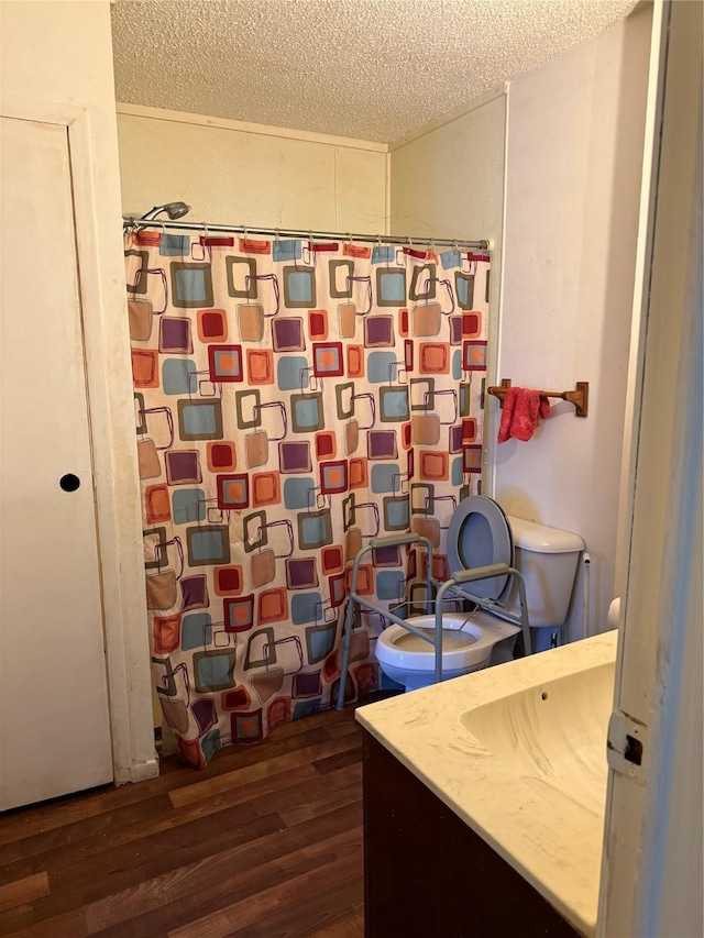 bathroom featuring toilet, vanity, wood-type flooring, and a textured ceiling