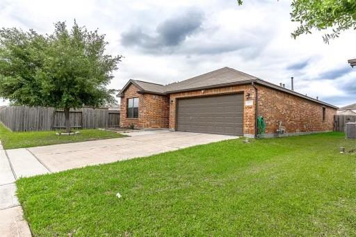 view of front of house featuring a garage, a front lawn, and central AC unit