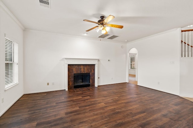 unfurnished living room with ceiling fan, dark wood-type flooring, ornamental molding, and a fireplace