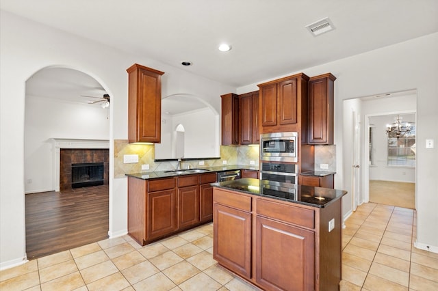 kitchen with a kitchen island, stainless steel appliances, a fireplace, sink, and light tile patterned floors