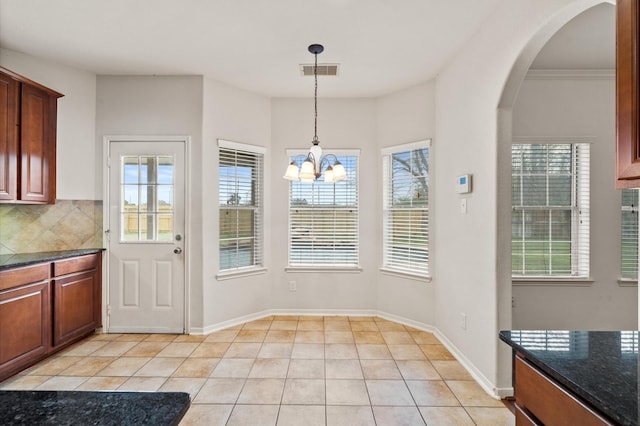 unfurnished dining area with ornamental molding, a chandelier, and light tile patterned flooring