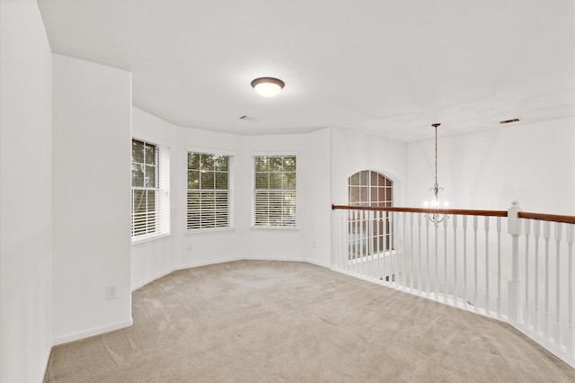 carpeted spare room featuring a notable chandelier