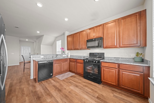 kitchen featuring light hardwood / wood-style floors, black appliances, kitchen peninsula, sink, and light stone countertops