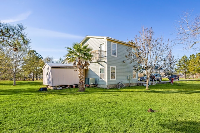 back of house featuring a balcony, a lawn, and central air condition unit