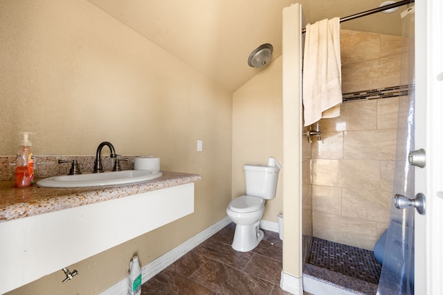 bathroom featuring lofted ceiling, vanity, toilet, and tiled shower