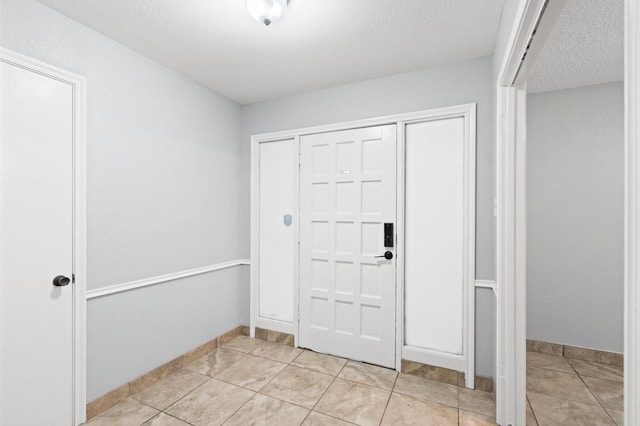 foyer entrance featuring a textured ceiling and light tile patterned floors