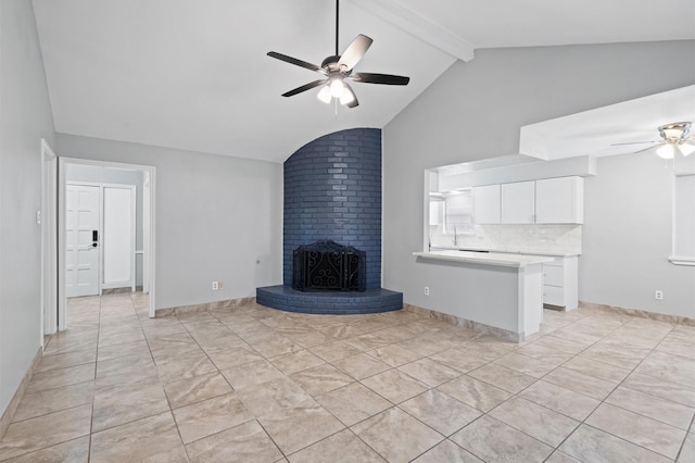 unfurnished living room with a brick fireplace, lofted ceiling with beams, and ceiling fan