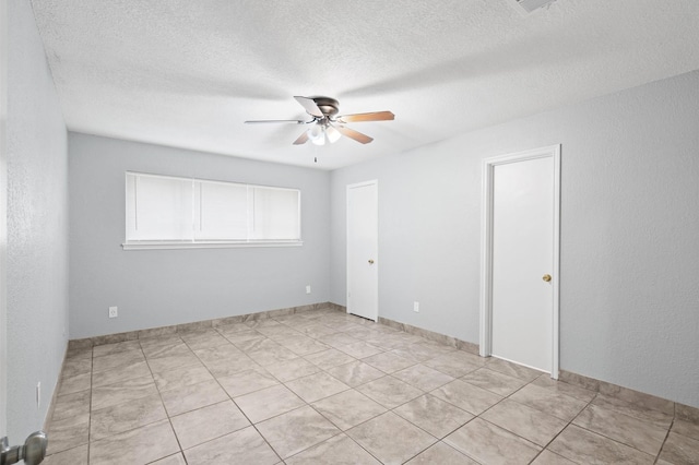 spare room with a textured ceiling, ceiling fan, and light tile patterned floors