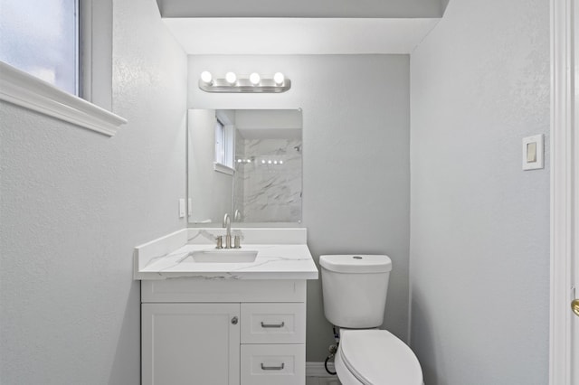 bathroom with toilet, vanity, and walk in shower