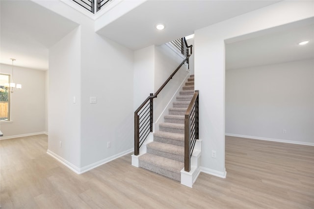 stairway with hardwood / wood-style flooring and a notable chandelier