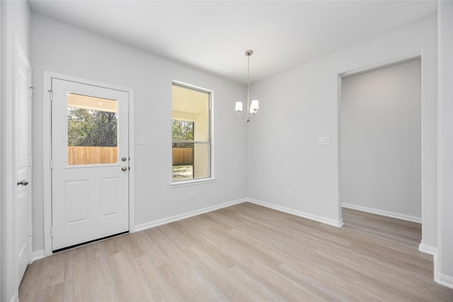 unfurnished dining area with an inviting chandelier and light hardwood / wood-style flooring