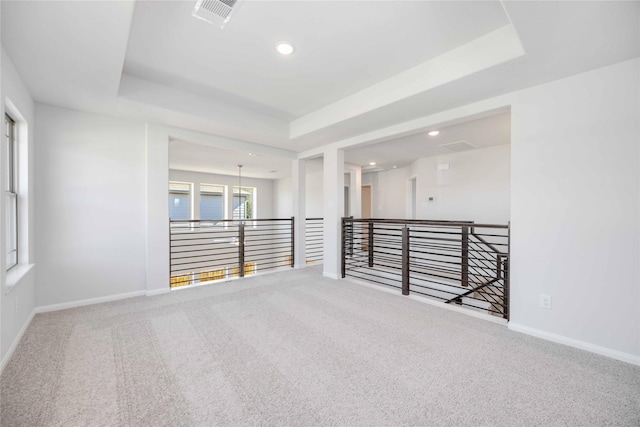 carpeted spare room featuring a tray ceiling