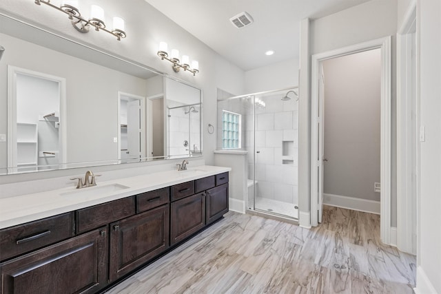 bathroom featuring a shower with shower door and vanity