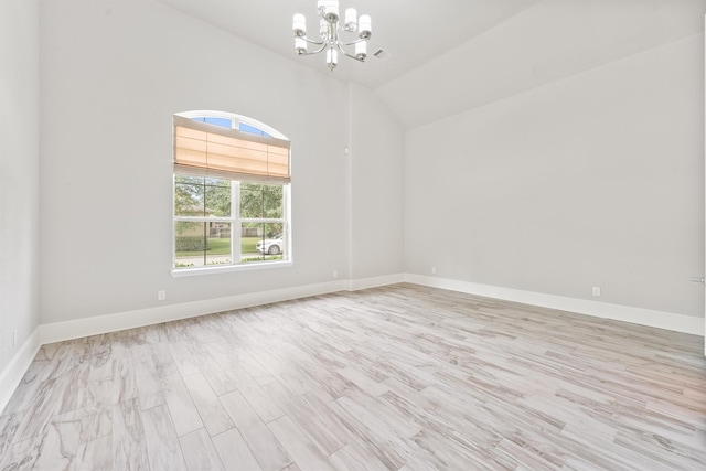 spare room featuring light hardwood / wood-style flooring, an inviting chandelier, and vaulted ceiling