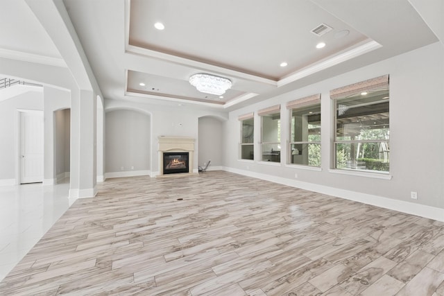 unfurnished living room with a chandelier, crown molding, light hardwood / wood-style flooring, and a tray ceiling