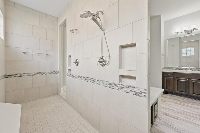 bathroom with hardwood / wood-style flooring, vanity, and a tile shower