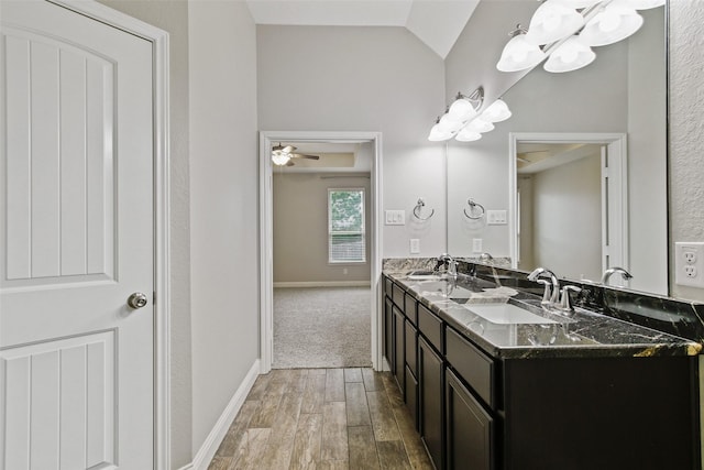 bathroom with lofted ceiling, wood finished floors, a sink, and baseboards