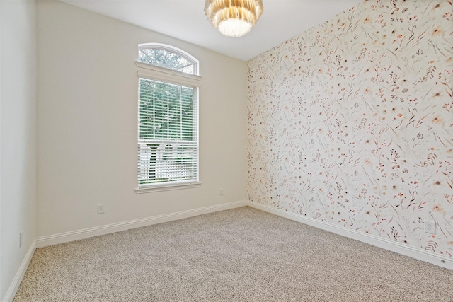 spare room with wallpapered walls, carpet, and baseboards