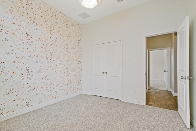 unfurnished bedroom featuring carpet, a closet, baseboards, and wallpapered walls