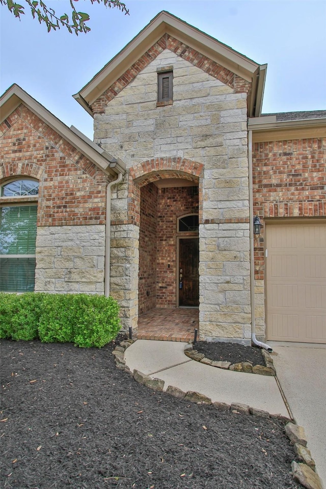 view of front of home featuring stone siding, brick siding, and an attached garage