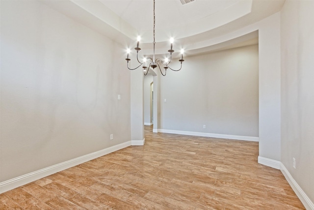 unfurnished room featuring a notable chandelier, light wood-type flooring, and baseboards