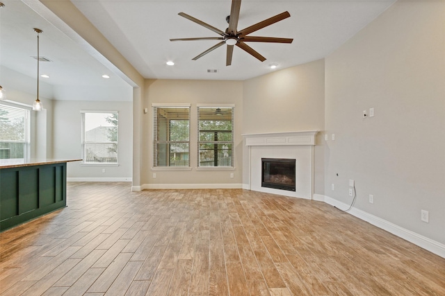 unfurnished living room with baseboards, light wood-style flooring, visible vents, and a tiled fireplace