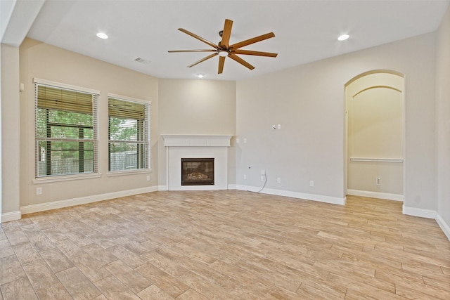 unfurnished living room featuring recessed lighting, a ceiling fan, a glass covered fireplace, light wood-type flooring, and baseboards