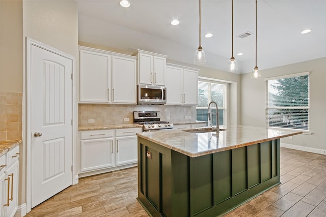 kitchen with stainless steel appliances, white cabinets, a sink, and backsplash