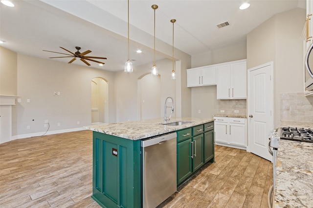 kitchen featuring arched walkways, stainless steel appliances, white cabinetry, a sink, and green cabinetry