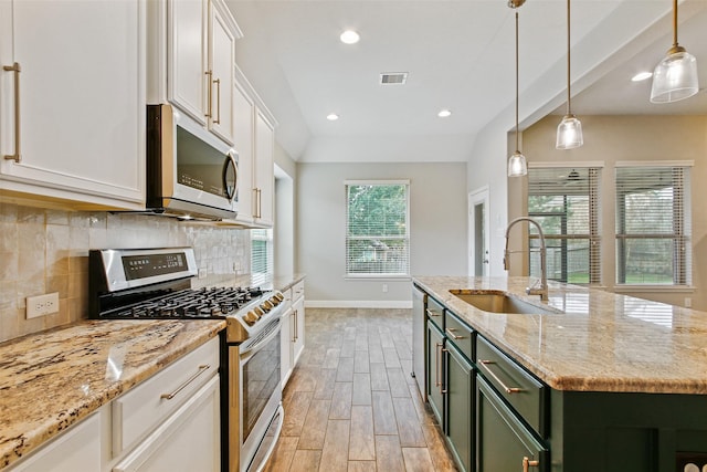 kitchen featuring stainless steel appliances, wood finish floors, a sink, visible vents, and white cabinets