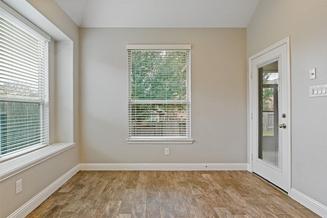 empty room featuring vaulted ceiling, baseboards, and wood finished floors