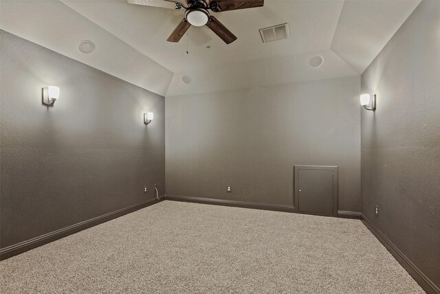 empty room featuring ceiling fan, visible vents, baseboards, vaulted ceiling, and carpet