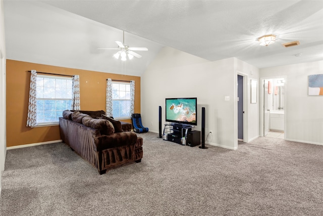 carpeted living room with ceiling fan and vaulted ceiling