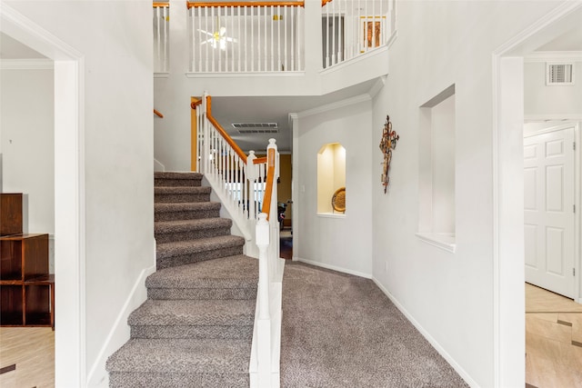 staircase with a high ceiling and ornamental molding