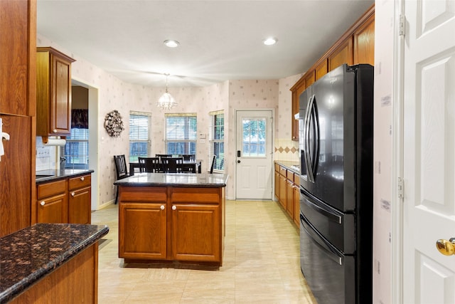 kitchen featuring an inviting chandelier, tasteful backsplash, black fridge with ice dispenser, pendant lighting, and a center island