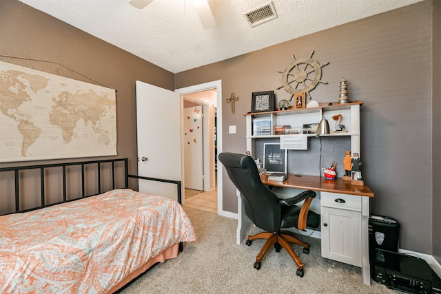 bedroom featuring ceiling fan, light carpet, and a textured ceiling