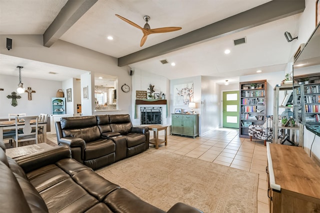 tiled living room with ceiling fan, vaulted ceiling with beams, and a fireplace