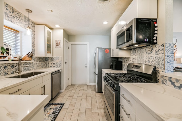 kitchen featuring backsplash, sink, white cabinetry, hanging light fixtures, and appliances with stainless steel finishes