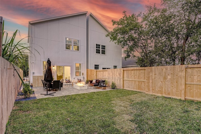 back house at dusk with a patio area, an outdoor fire pit, and a lawn