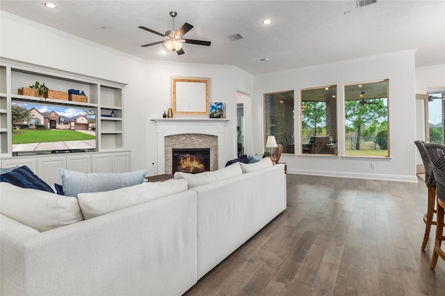 living room featuring ceiling fan, a fireplace, ornamental molding, and dark hardwood / wood-style floors