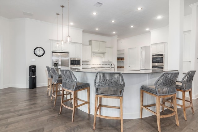 kitchen with white cabinetry, hanging light fixtures, a kitchen bar, and stainless steel appliances