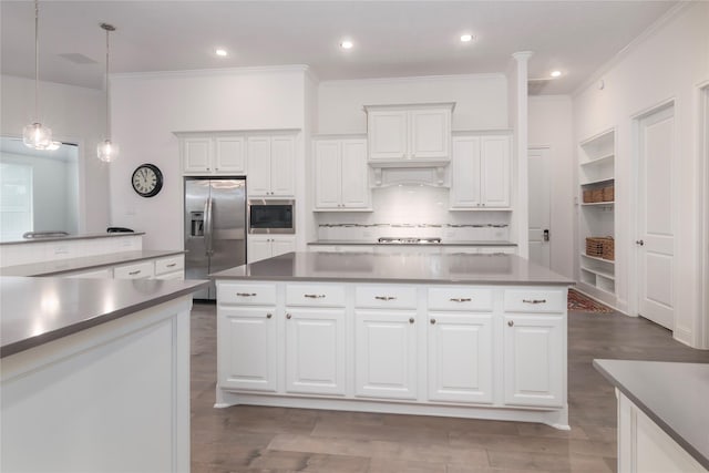 kitchen with decorative light fixtures, a center island, decorative backsplash, appliances with stainless steel finishes, and white cabinets