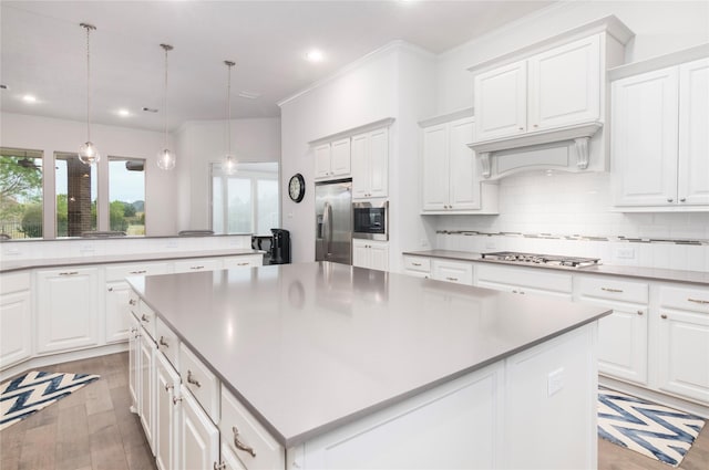 kitchen with white cabinetry, light hardwood / wood-style floors, stainless steel appliances, a kitchen island, and pendant lighting