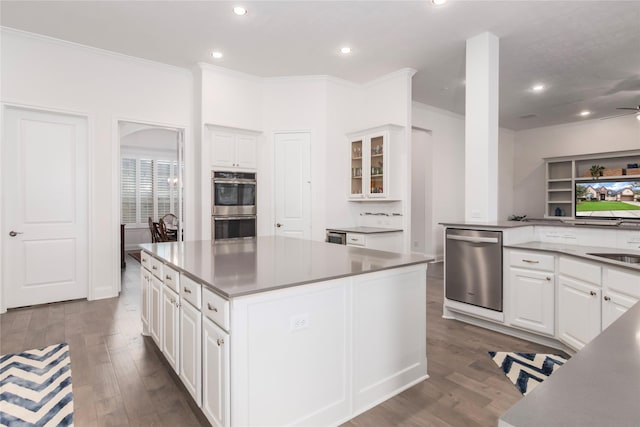 kitchen featuring white cabinets, a kitchen island, dark hardwood / wood-style flooring, stainless steel appliances, and ornamental molding