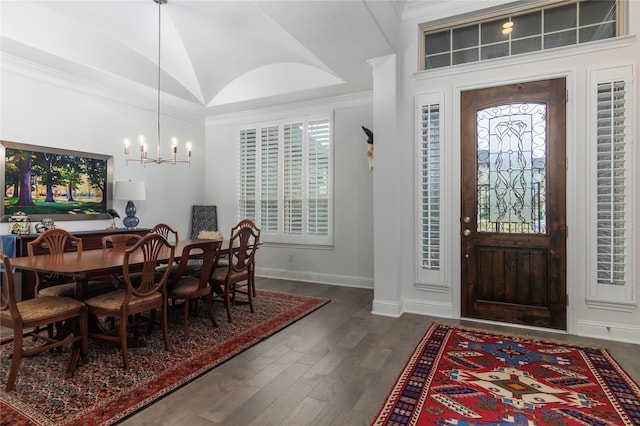 entrance foyer with dark wood-type flooring, vaulted ceiling, a notable chandelier, and ornamental molding