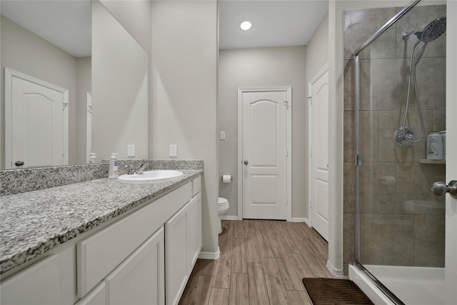 bathroom featuring toilet, vanity, and a shower with door