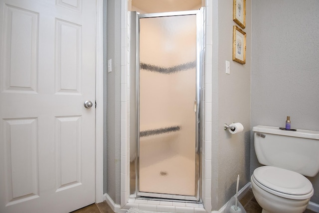 bathroom with toilet and a shower with shower door