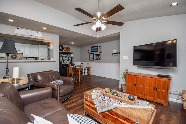 living room with ceiling fan, a textured ceiling, and dark hardwood / wood-style floors