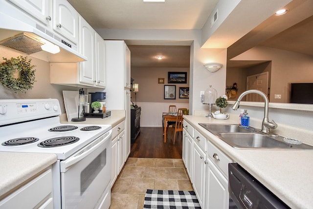 kitchen featuring dishwasher, electric range, sink, light tile patterned floors, and white cabinets